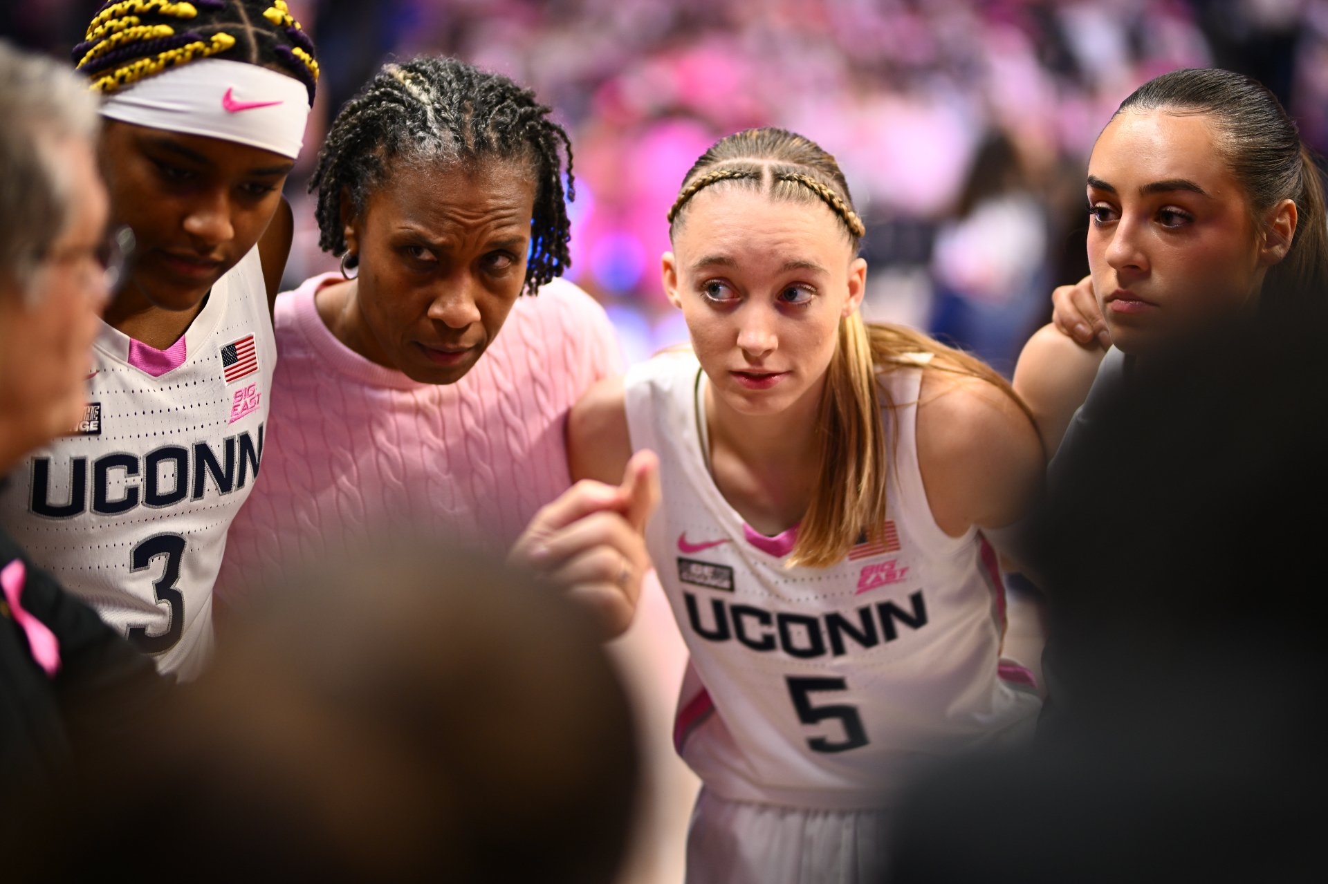 Jamelle Elliott in a courtside huddle with Paige Bueckers and UConn players